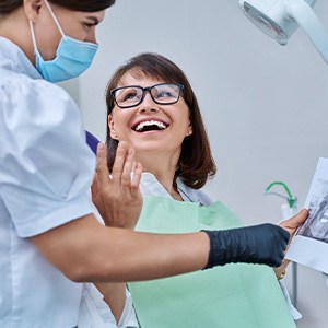 Woman smiling with dentist while reviewing X-ray