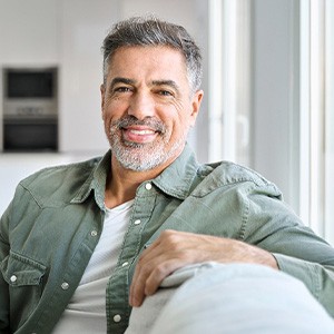 Senior man smiling while sitting on couch