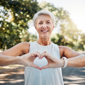 Smiling lady makes shape of heart with her hands